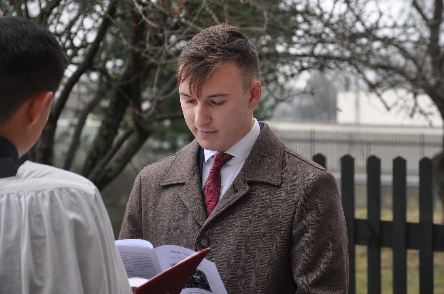 Alfonso Menanno in a brown coat participating in an outdoor baptism
