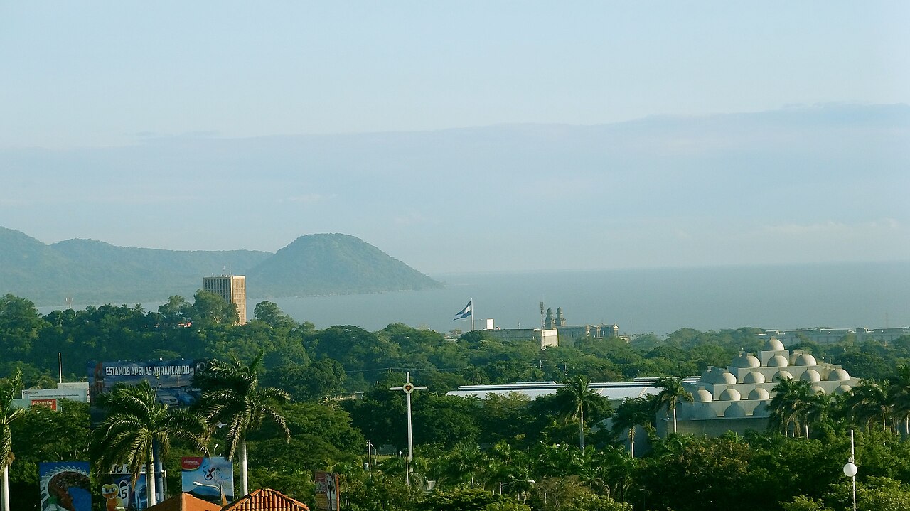 Green Managua cityscape with the domed cathedral, Nicaraguan flag, Lake Managua and hills beyond