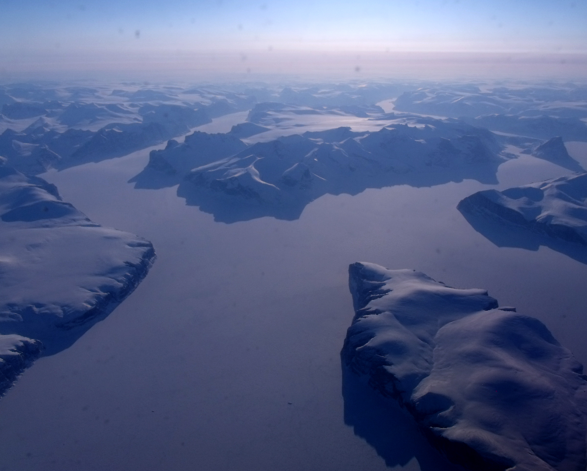 Aerial view of snow-covered mountains and frozen fjords on the approach to Pond Inlet, Nunavut